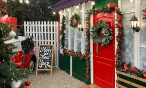 Un angolo magico per idee per mercatini di natale fai da te: un albero addobbato, una lavagna con "Happy New Year" e una casetta decorata a festa.