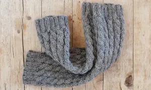 Un caldo scaldacollo grigio lavorato a maglia con trecce. Perfetto per scoprire cosa fare con 100 grammi di lana.
