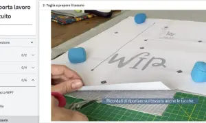 Taglio di diversi tipi di tessuto a righe e fantasia, con forbici e cartamodello per una sacca WIP.