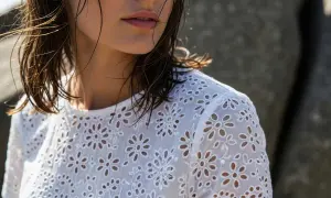 Dettaglio di una donna con capelli bagnati che indossa una blusa bianca con un delicato pizzo di San Gallo.