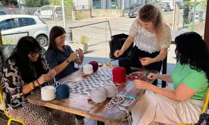 Donne lavorano a maglia con gomitoli di lana colorata al **café lana**.