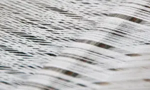Fili bianchi di cotone organico intrecciati, creando un motivo a rete morbido e naturale.