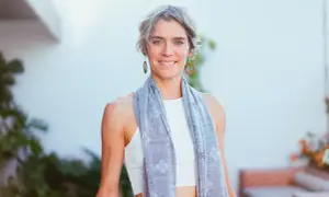 Donna sorridente con sciarpa grigia, un esempio di quanto deve essere lunga una sciarpa da donna per un look casual e chic.