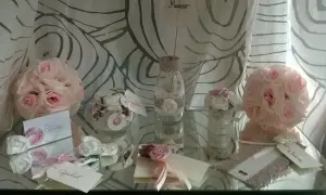 Segnaposto matrimonio fai da te shabby chic: rose rosa e bianche, vasetti decorati con pizzo, biglietti con nomi.