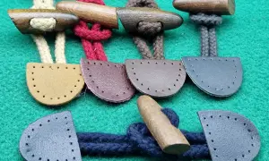 Bottoni alamari fai da te in legno e pelle, pronti per essere cuciti su capi d'abbigliamento.