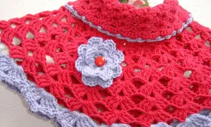 Elegante scaldacollo uncinetto fucsia con bordo e fiorellino lilla.