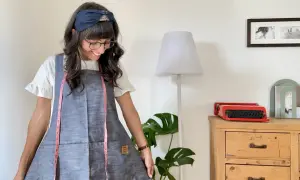 Donna sorridente con grembiule giapponese, un metro da sarta rosa appeso al collo. Un cartamodello gratis per crearlo!
