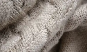 Trama a trecce di un maglione in pura lana vergine, morbido e caldo al tatto.
