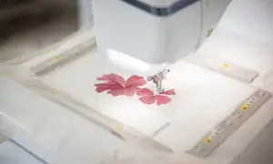 Macchina da cucire ricama un fiore rosso su un sottile tulle materiale.