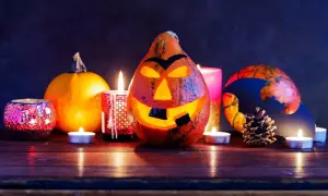 Un terrificante centrotavola Halloween fai da te con zucche intagliate, candele e decorazioni spettrali.