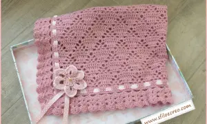 Copertina rosa all'uncinetto per carrozzina, con fiore e nastri. Schemi facili per creare un capolavoro.
