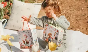 Bambina con due scatole di puzzle ad acqua, perfetti per le attività estive. Un coniglietto in bici e un orsetto giardiniere animano i giochi.
