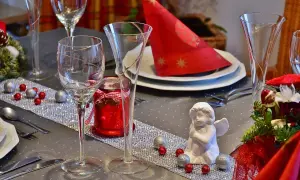 Un centrotavola con fiori fai da te, decorato con palline rosse e argentate, un angioletto e candele rosse, pronto per un'occasione speciale.