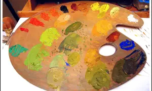Tavolozza di un artista con vari tipi di colori: verdi, gialli, arancioni, rossi, blu e neri.