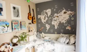 Camera da letto con mappa del mondo e decorazioni tema viaggio: aerei, mongolfiere, animali e chitarre.