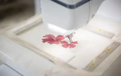 Macchina da cucire ricama un fiore rosso su un sottile tulle materiale.