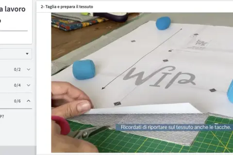Taglio di diversi tipi di tessuto a righe e fantasia, con forbici e cartamodello per una sacca WIP.