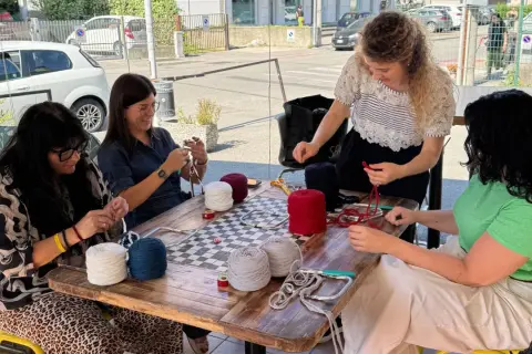 Donne lavorano a maglia con gomitoli di lana colorata al **café lana**.