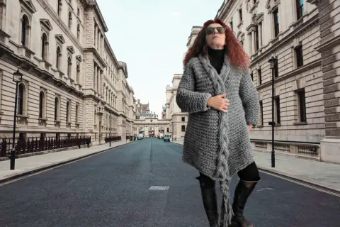 Donna con cappotto di lana grossa ai ferri, in una strada di Londra.