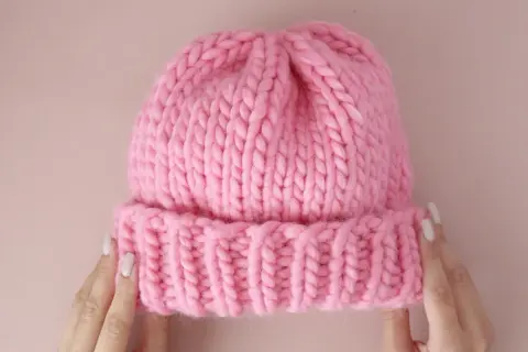Morbida cuffietta neonato ai ferri, rosa acceso, con bordino a coste. Perfetta per tenere al caldo la testa del tuo piccolo.