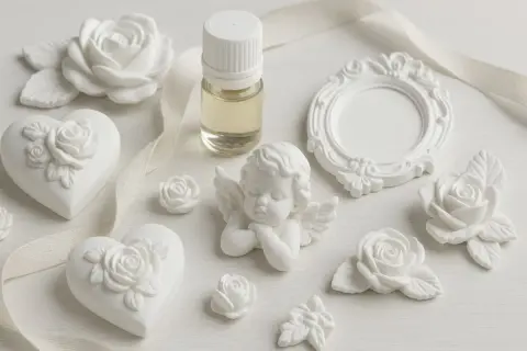 Gessetti per bomboniere: cuori, rose, angioletto e cornice in gesso bianco, con boccetta di profumo.
