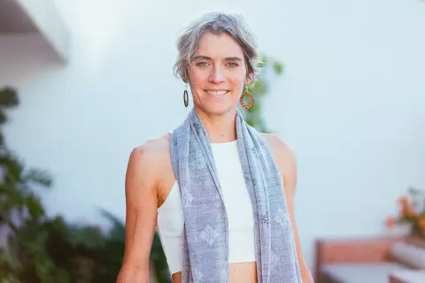 Donna sorridente con sciarpa grigia, un esempio di quanto deve essere lunga una sciarpa da donna per un look casual e chic.