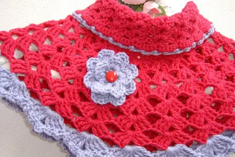 Elegante scaldacollo uncinetto fucsia con bordo e fiorellino lilla.