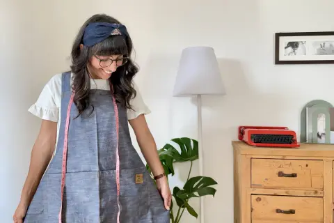 Donna sorridente con grembiule giapponese, un metro da sarta rosa appeso al collo. Un cartamodello gratis per crearlo!