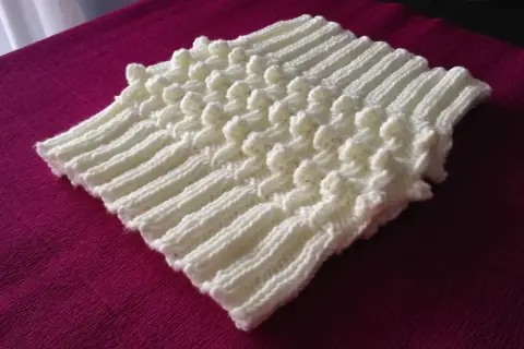 Scaldacollo ai ferri con motivo a popcorn, perfetto per chi cerca schemi gratis per creare un capo caldo e alla moda.