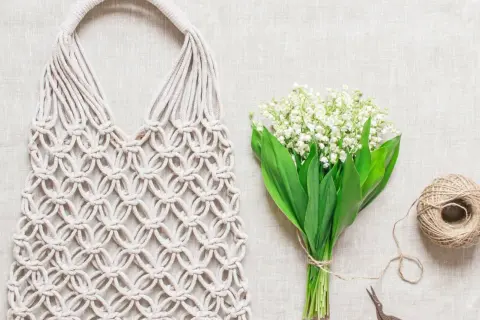Borse macramè fatte a mano, con spago e fiori di mughetto, pronte per le istruzioni creative.