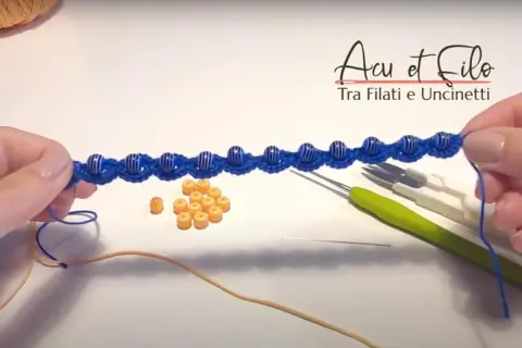 Bracciali all'uncinetto schemi gratis: un lavoro in corso con perline blu e arancioni, uncinetti e filo.