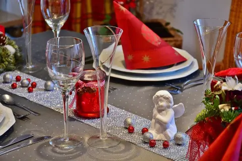 Un centrotavola con fiori fai da te, decorato con palline rosse e argentate, un angioletto e candele rosse, pronto per un'occasione speciale.