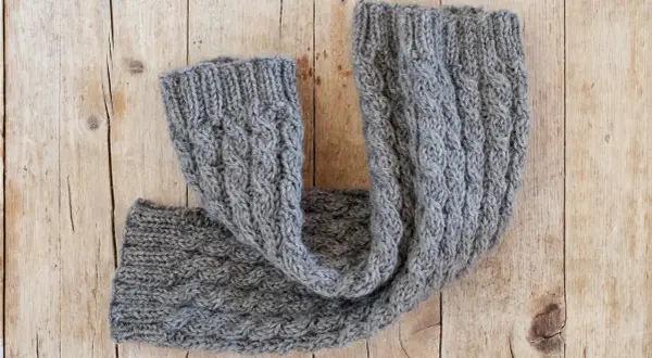 Un caldo scaldacollo grigio lavorato a maglia con trecce. Perfetto per scoprire cosa fare con 100 grammi di lana.