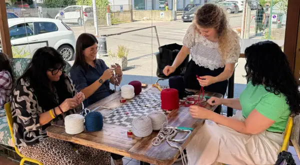 Donne lavorano a maglia con gomitoli di lana colorata al **café lana**.