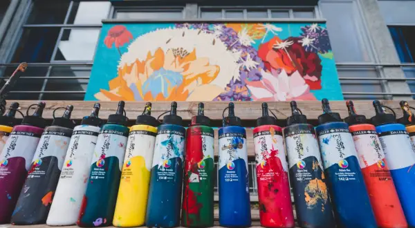 Flaconi di colori acrilici Daler Rowney, con vivaci **colori contrastanti** che riflettono la pittura floreale sullo sfondo.