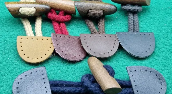 Bottoni alamari fai da te in legno e pelle, pronti per essere cuciti su capi d'abbigliamento.