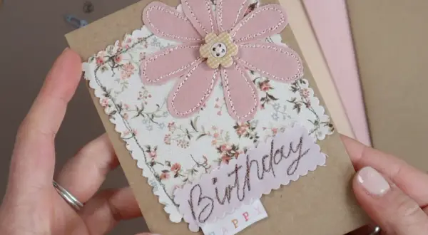 Biglietto d'auguri con fiore rosa in tessuto e scritta "Birthday". Perfetto per creare decorazioni per biglietti uniche e personalizzate.