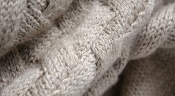 Trama a trecce di un maglione in pura lana vergine, morbido e caldo al tatto.