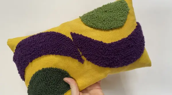 Cuscino rettangolare giallo con motivi astratti in microspugna viola e verde.