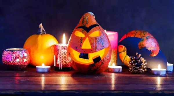 Un terrificante centrotavola Halloween fai da te con zucche intagliate, candele e decorazioni spettrali.