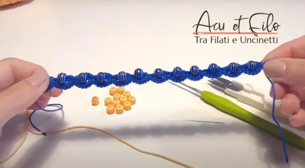 Bracciali all'uncinetto schemi gratis: un lavoro in corso con perline blu e arancioni, uncinetti e filo.