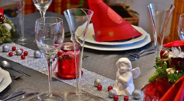 Un centrotavola con fiori fai da te, decorato con palline rosse e argentate, un angioletto e candele rosse, pronto per un'occasione speciale.