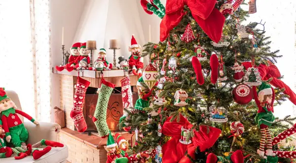 Albero di Natale addobbato con elfi, calze e fiocchi rossi. Un esempio di come decorare l'albero di natale fai da te con tanti dettagli.