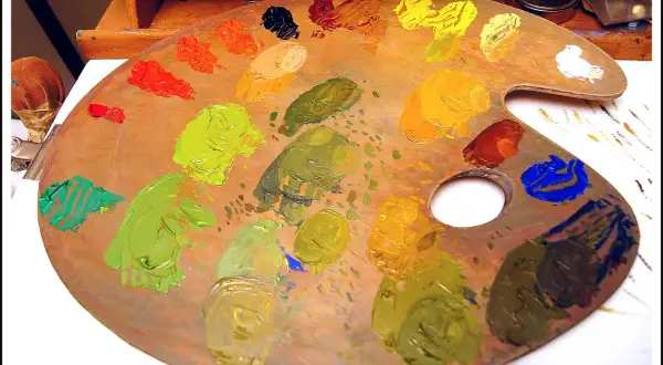 Tavolozza di un artista con vari tipi di colori: verdi, gialli, arancioni, rossi, blu e neri.