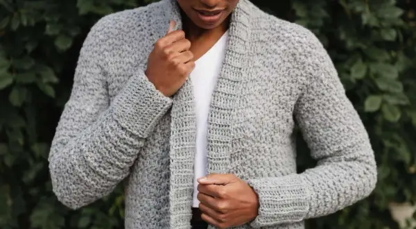 Donna con cardigan grigio all'uncinetto, perfetto per chi cerca schemi gratis per creare capi unici.