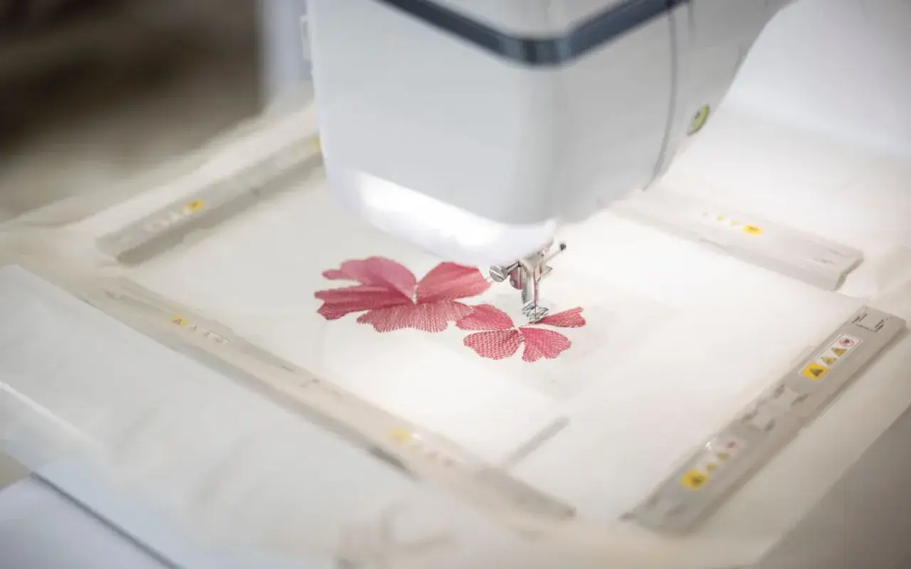 Macchina da cucire ricama un fiore rosso su un sottile tulle materiale.