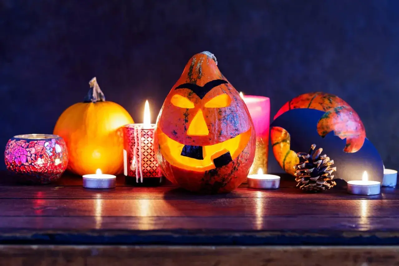 Un terrificante centrotavola Halloween fai da te con zucche intagliate, candele e decorazioni spettrali.