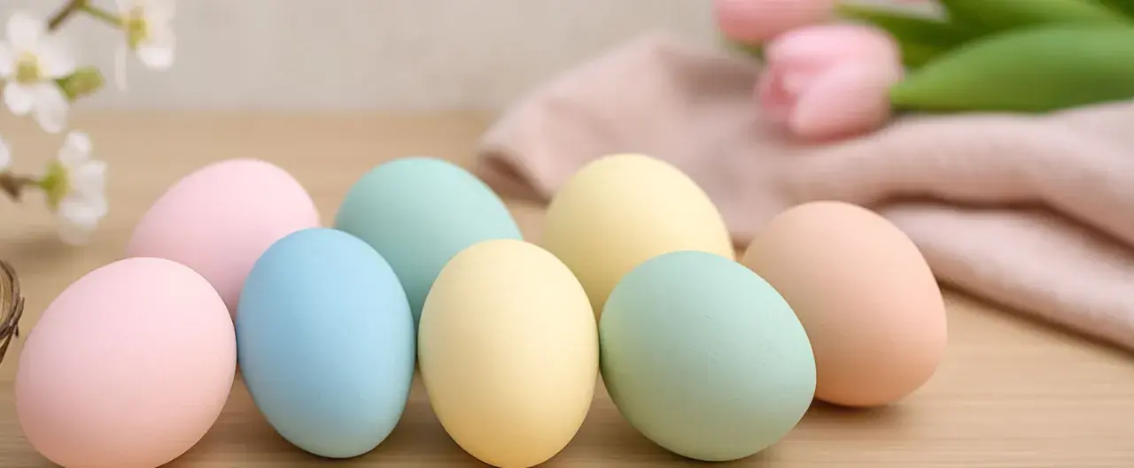 Uova di Pasqua in tenui colori pastello: rosa, azzurro, giallo e verde menta, pronte per essere decorate.