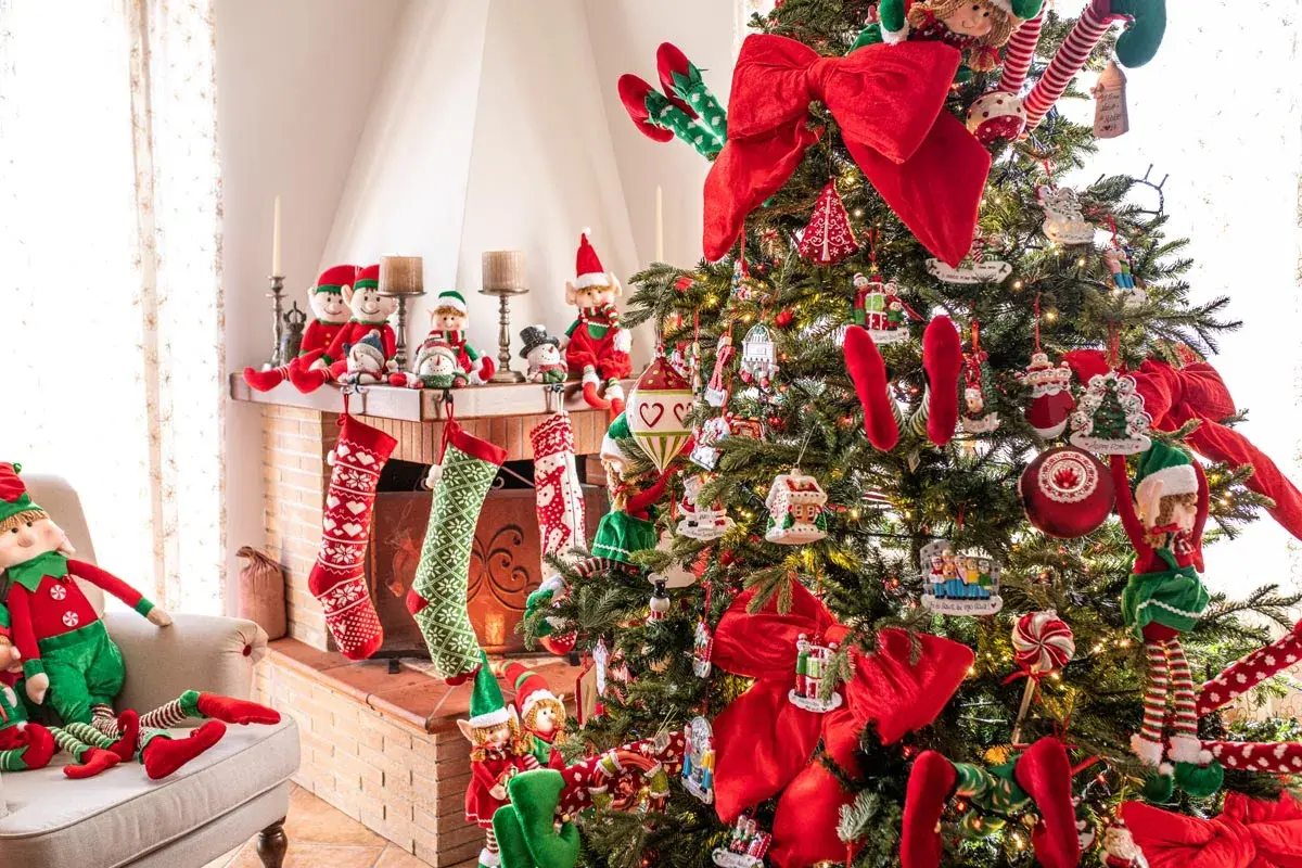 Albero di Natale addobbato con elfi, calze e fiocchi rossi. Un esempio di come decorare l'albero di natale fai da te con tanti dettagli.