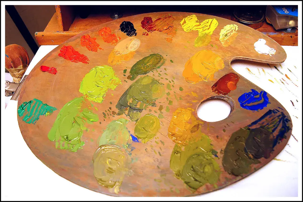 Tavolozza di un artista con vari tipi di colori: verdi, gialli, arancioni, rossi, blu e neri.